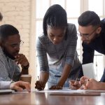 Group of professionals gather around a table working together